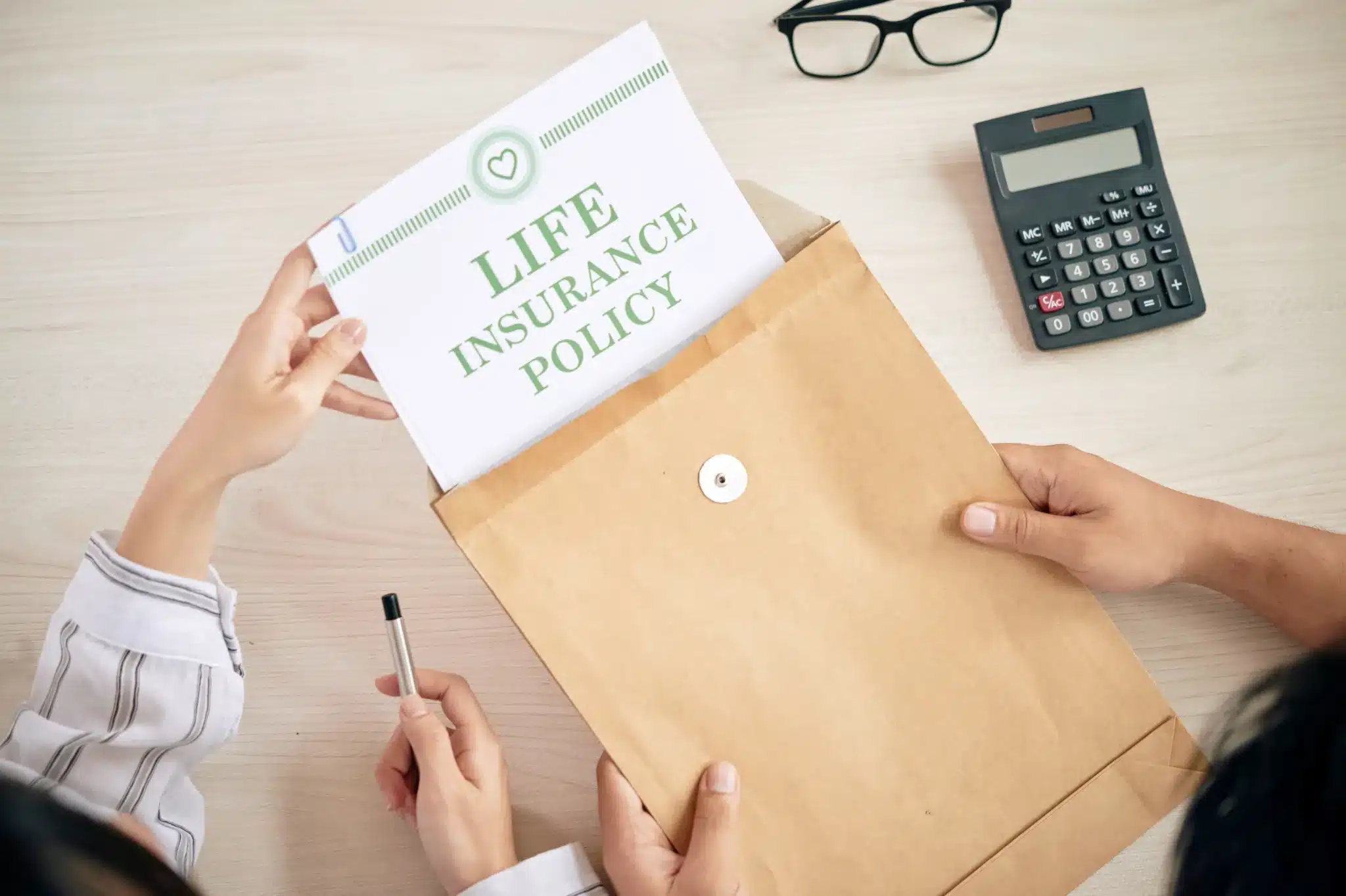 Life insurance in Dubai envelope on desk with calculator and glasses.